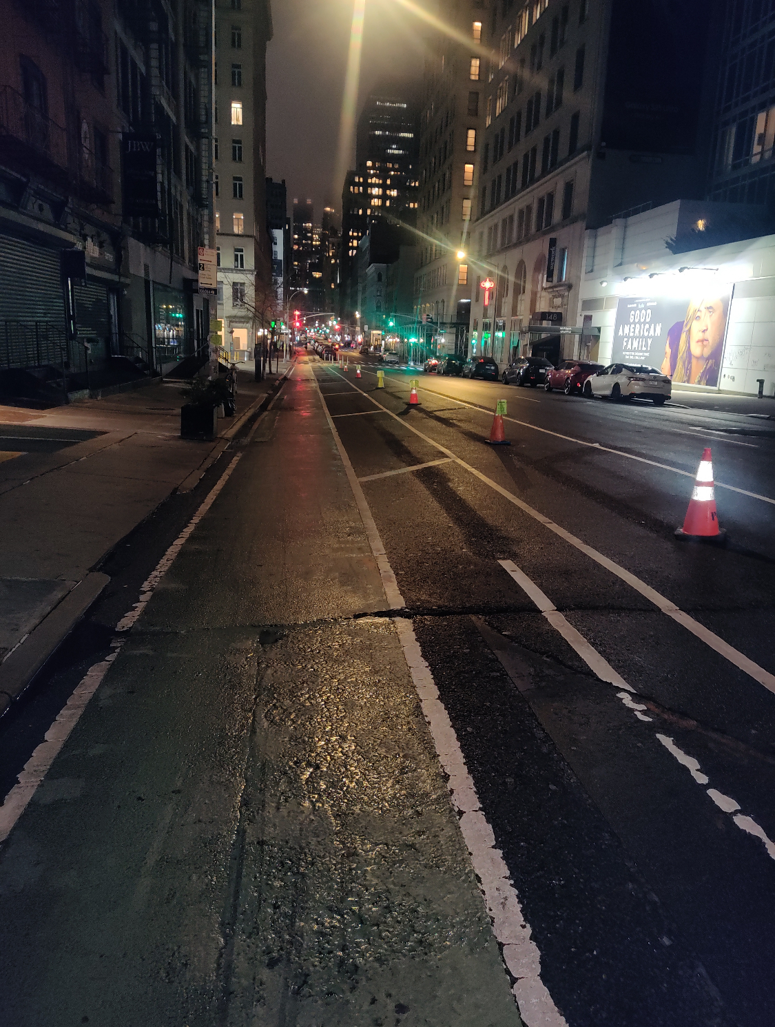 Orange cones holding lanes on NYC avenue at night